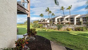 A hotel with a view of the ocean, featuring a well-maintained lawn, palm trees, and a modern building facade.