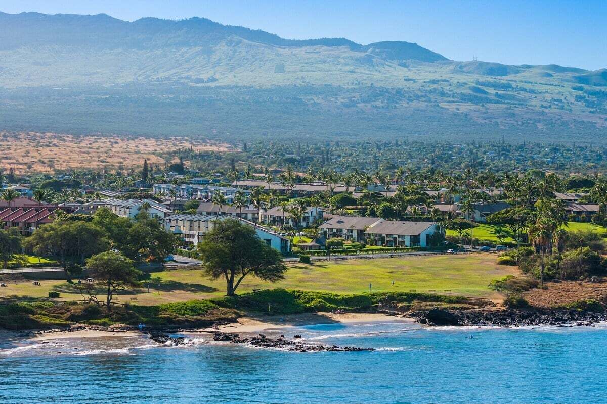 Eine Küstenstadt mit Strandhäusern, freiem Blick auf den Ozean und einer Hügelkulisse.
