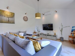 Una sala de estar moderna con sofá, televisión, obras de arte e iluminación decorativa.