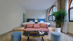 A hotel room with two beds, a sofa, a round table with a tray, and a potted plant. - Living Sense Linghai Hotel (Xiamen)