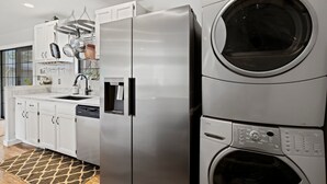 Una cocina con un refrigerador de acero inoxidable, lavavajillas y lavadora y secadora apiladas.