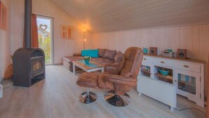 A cozy living room with a fireplace, leather sofa, coffee table, and a white cabinet with drawers. - Ferienhaus im Ferienpark Mirow (Mirow)