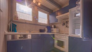 A compact kitchen with a built-in oven, a microwave, and a refrigerator. - Ferienhaus im Ferienpark Mirow (Mirow)