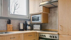 Una cocina compacta con armarios de madera, un microondas, una cafetera y un horno.