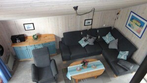 A compact living space with a sofa, a chair, a small table, and a kitchenette area. - Ferienhaus im Skandinavischen Stil (Mirow)