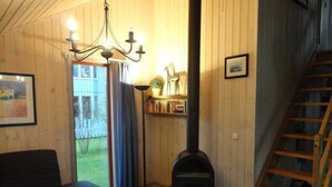 A cozy room with a fireplace, a sofa, a table with flowers, and a staircase. - Ferienhaus im Skandinavischen Stil (Mirow)