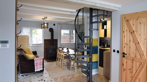 A cozy living room with a fireplace, a dining area, and a spiral staircase leading to an upper level.