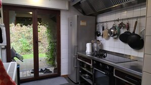 Una cocina moderna con estufa a gas, horno y ollas colgantes.