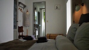 Un dormitorio con cama, una silla, una lámpara y un armario.