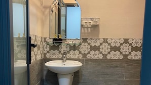 A bathroom with a pedestal sink, a toilet, and a mirror. - Bunk Beach Hostel (Da Nang)