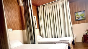 A hotel room with two beds, wooden paneling on the walls, a painting on the wall, and a wooden floor. - Bunk Beach Hostel (Da Nang)