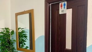 A wooden door with a WC sign, a mirror, and a potted plant. - Bunk Beach Hostel (Da Nang)