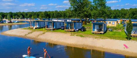 A lakeside camp with floating cabins and paddleboarders on the water.