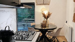 Una cucina moderna con piano cottura a gas, sedie nere, un tavolo rotondo e una lampada a sospensione.
