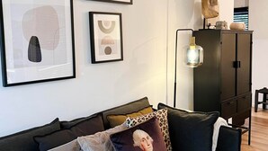Un soggiorno moderno con un divano dai colori scuri, un mobile contenitore in legno e un'opera d'arte astratta a parete.