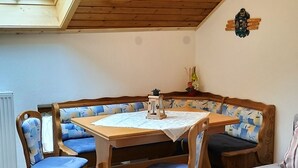 A cozy corner with a wooden table and bench, a small lantern, and a view through a skylight. - Apartment 50 sqm with separate bedroom and balcony (Aschau im Chiemgau)
