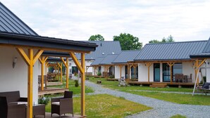 Een rij moderne, gelijkvloerse bungalows met houten balkons en buiten zitgedeeltes.