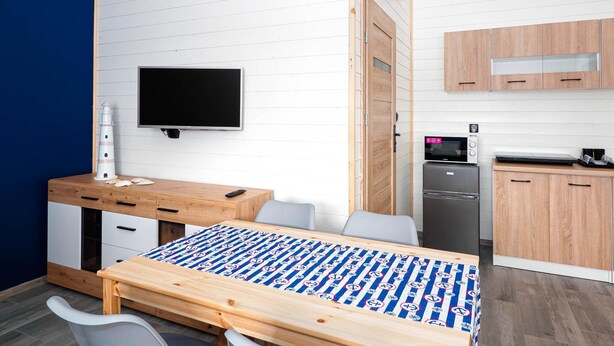 Ein kleines Zimmer mit einem Bett, einem Schreibtisch, einem Fernseher, einer Mikrowelle und einer kleinen Küchenzeile.