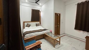 Ein Schlafzimmer mit einem Bett, einer hölzernen Bank, einem kleinen Tisch, einem Deckenventilator und einer Tür.