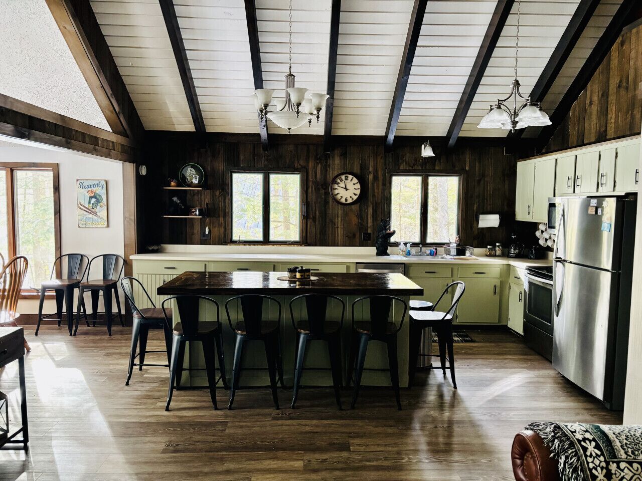 Een keuken met een centraal eiland, houten balken en een klok aan de muur.