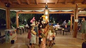 A covered outdoor area with wooden beams and tables, a large mascot character, and people gathered around. - Farmhouse in Vieste Near Gargano Park (Vieste)