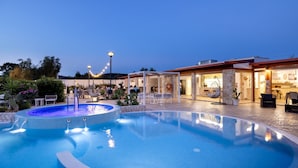 A swimming pool with a water fountain, surrounded by outdoor seating and a restaurant. - Farmhouse in Vieste Near Gargano Park (Vieste)