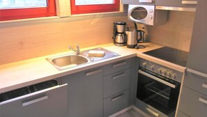 A compact kitchen with a sink, a coffee maker, a microwave, and an oven. - Exklusives Skandinavisches Ferienhaus (Mirow)