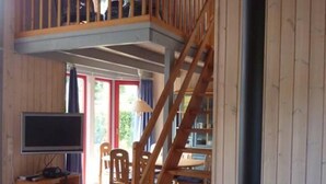 A wooden interior with a fireplace, a TV, and a dining area. - Exklusives Skandinavisches Ferienhaus (Mirow)