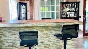 A kitchen with a wooden ceiling, stone backsplash, and two bar stools.