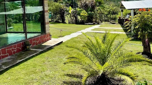 A house with a large glass window, a well-maintained lawn, and a view of mountains in the background.