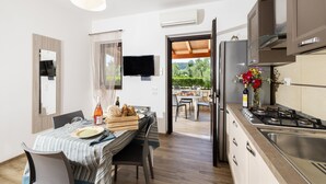 A modern kitchen with a dining area, a TV, and a view to an outdoor patio. - Farmhouse in Vieste Near Gargano Coast (Vieste)