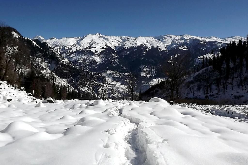 Un paisaje montañoso cubierto de nieve con cielo despejado.