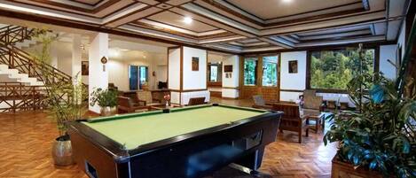 A pool table in a room with wooden floors and a staircase.