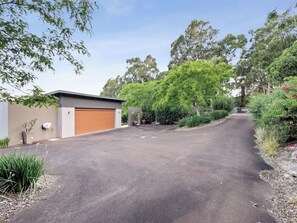 A residential driveway leading to a garage, surrounded by greenery and trees. - Cohala—Luxe Hillside Retreat with Theatre & Garden (Yallingup)