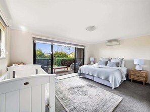 A bedroom with a bed, bedside tables, a window, and a view of greenery.