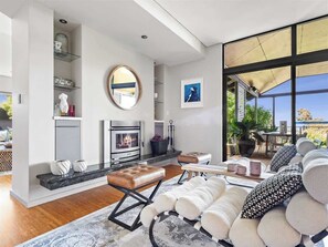 A modern living room with a fireplace, seating area, and large windows. - Cohala—Luxe Hillside Retreat with Theatre & Garden (Yallingup)