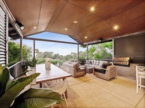 An outdoor patio with a dining table, sofas, and a grill area. - Cohala—Luxe Hillside Retreat with Theatre & Garden (Yallingup)