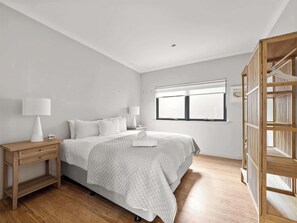A bedroom with a bed, bedside tables, a window, and a wooden structure. - Cohala—Luxe Hillside Retreat with Theatre & Garden (Yallingup)