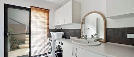 Una cocina moderna con lavadora integrada, un lavabo y un espejo grande.