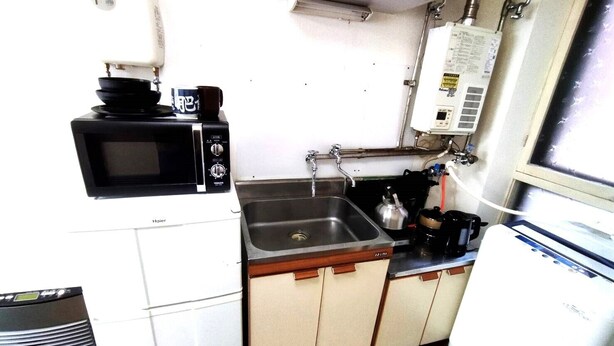 A compact kitchen with a microwave, sink, and a small refrigerator. - Nissho House 105 (Sapporo)