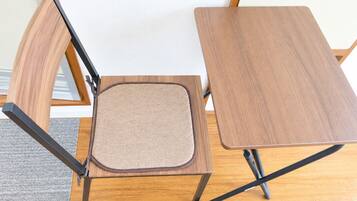 A foldable wooden chair with a cushioned seat and a matching wooden table.