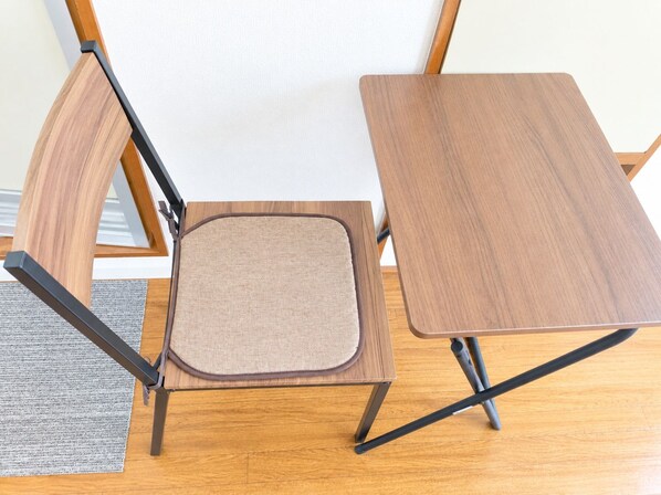 A foldable wooden chair with a cushioned seat and a matching wooden table. - Higashi-Sapporo Residence minpaku (Sapporo)