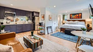 A modern apartment with a kitchen, a bedroom with a large bed, a dining area, and a living room with a sofa and coffee table.