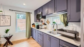 A modern kitchen with grey cabinets, stainless steel appliances, and a window with a view of the outdoors.