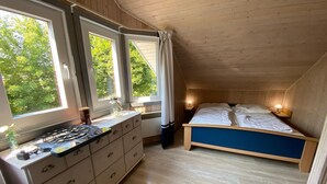 A bedroom with a bed, a dresser, and a window with curtains. - Exklusives Skandinavisches Ferienhaus (Mirow)