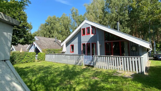 A two-story house with a sloped roof, a wooden fence, and a well-maintained lawn. - Exklusives Skandinavisches Ferienhaus (Mirow)