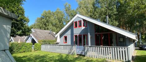 A two-story house with a sloped roof, a wooden fence, and a well-maintained lawn.