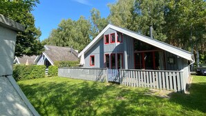 A two-story house with a sloped roof, a wooden fence, and a grassy yard. - Exklusives Skandinavisches Ferienhaus (Mirow)