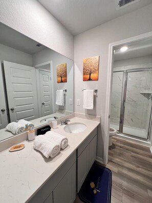 Un baño moderno con lavamanos doble, un espejo grande y cabina de ducha de vidrio.