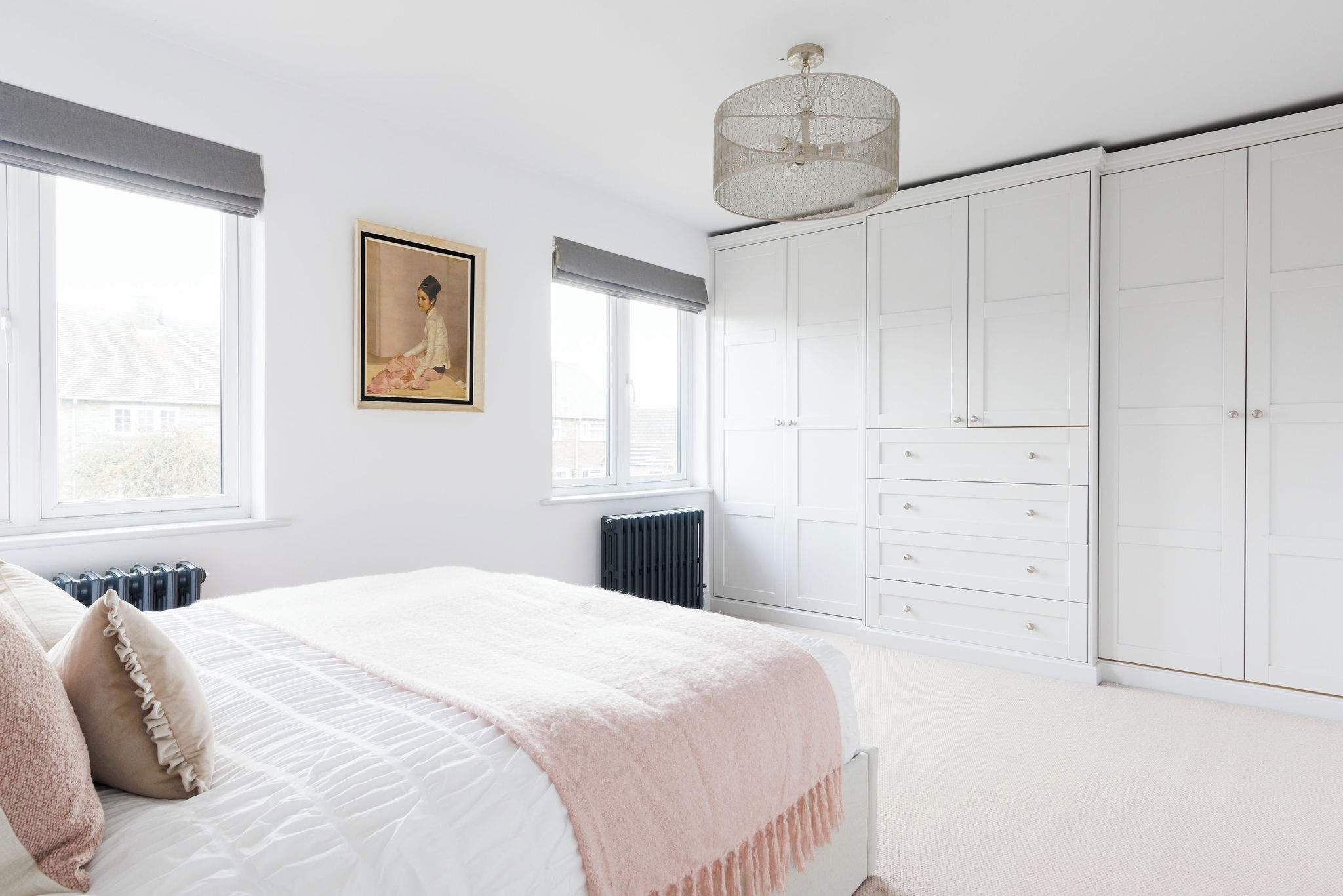 Quarto com cama, radiador, guarda-roupa e um quadro na parede.